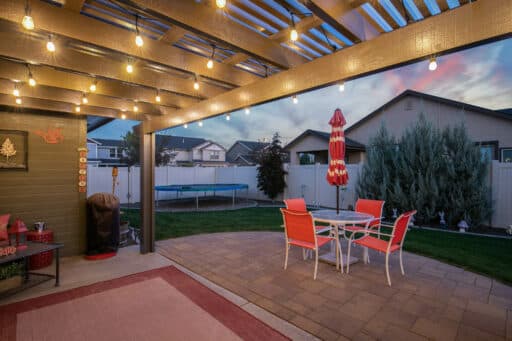 tan house with tan pergola and red patio furniture