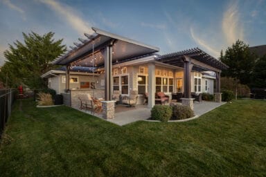 Tan patio cover and pergola in the background of a green lawn in Boise, Idaho.