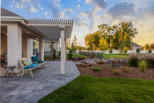 white pergola over grey stone patio with colorful patio furniture in blue