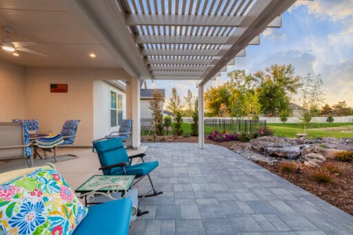 white pergola over grey stone patio with colorful patio furniture in blue in Boise, Idaho.