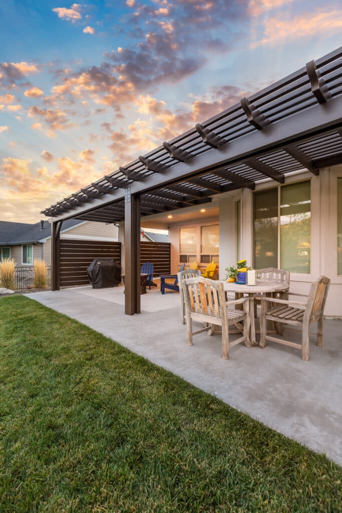 A brown pergola alongside a large home at the base of the foothills in Boise, Idaho with the focus on the patio.