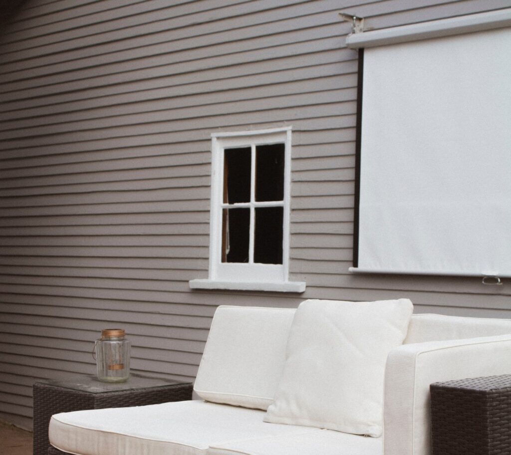White projector screen on an outdoor patio hanging from a grey home.